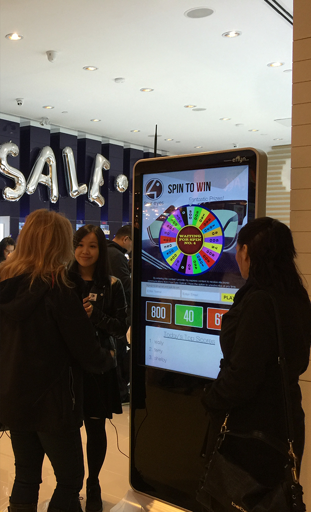Eflyn Free Standing Kiosk at Eyestar Optical people playing with the Spin To Win App